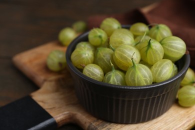 Photo of Fresh green gooseberries in bowl on table, closeup. Space for text