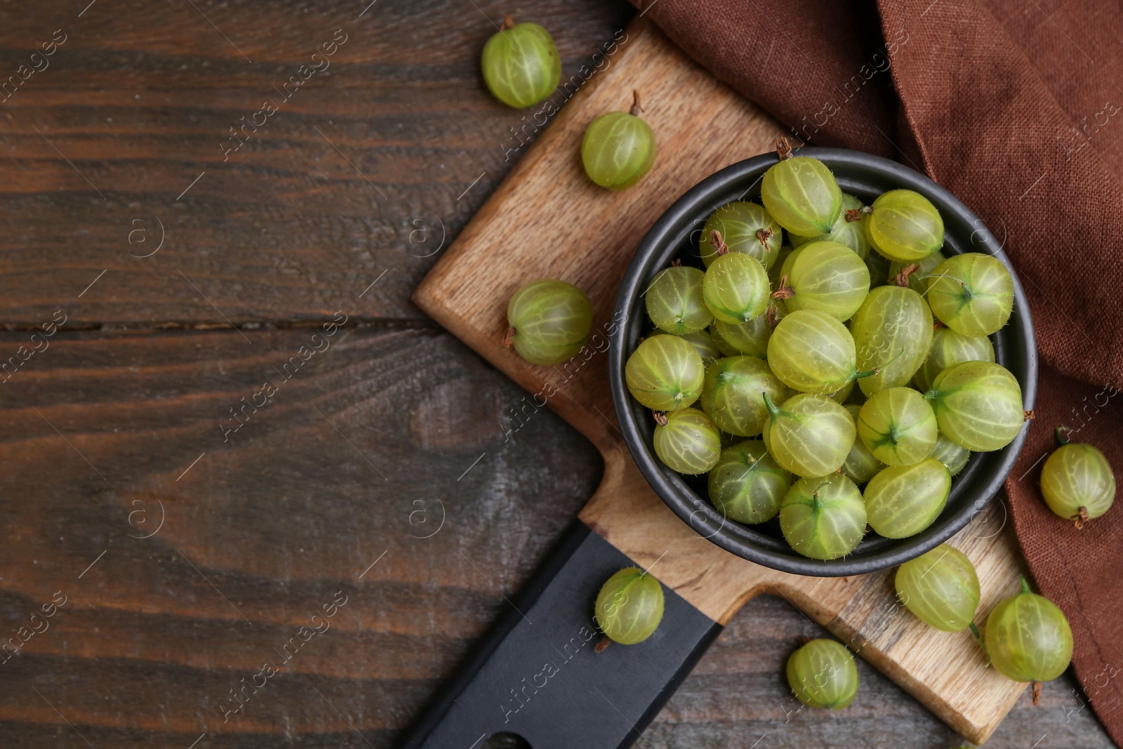 Fresh green gooseberries in bowl on wooden table, flat lay. Space for text Photo of Fresh green gooseberries in bowl on wooden table, flat lay. Space for text