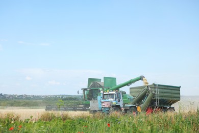 Photo of Combine harvester unloading wheat into tractor trailer in field