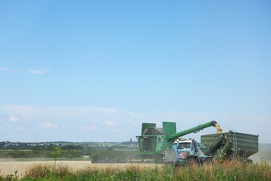 Photo of Combine harvester unloading wheat into tractor trailer in field