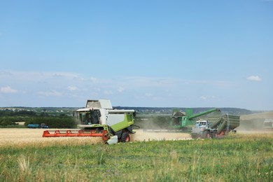 Photo of Modern combine harvesters and tractor working in wheat field