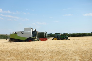 Photo of Combine harvester and tractor working in wheat field