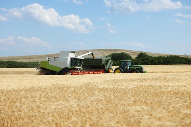 Photo of Combine harvester unloading wheat into tractor trailer in field