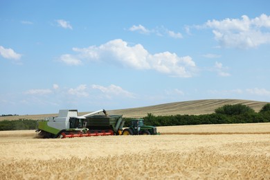 Photo of Combine harvester unloading wheat into tractor trailer in field