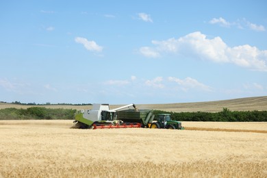 Photo of Combine harvester unloading wheat into tractor trailer in field
