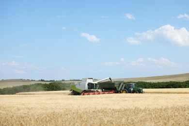 Photo of Combine harvester unloading wheat into tractor trailer in field