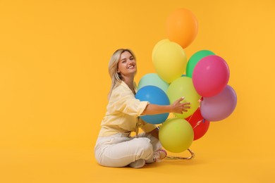 Photo of Happy woman with bunch of colorful balloons on yellow background