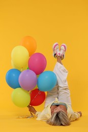 Photo of Woman with bunch of colorful balloons on yellow background