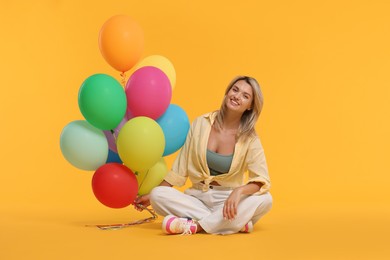 Photo of Happy woman with bunch of colorful balloons on yellow background