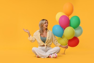 Photo of Happy woman with bunch of colorful balloons on yellow background