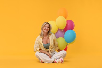 Photo of Happy woman with bunch of colorful balloons on yellow background