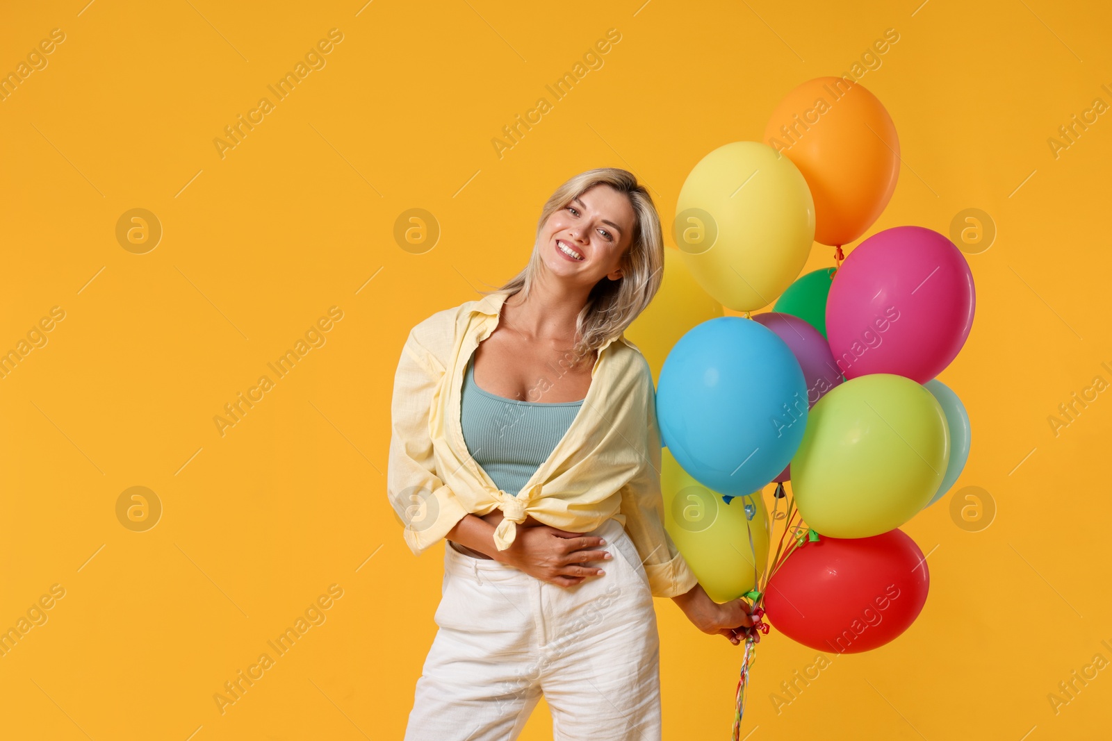Photo of Happy woman with bunch of colorful balloons on yellow background