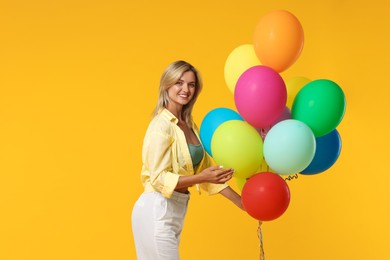 Photo of Happy woman with bunch of colorful balloons on yellow background