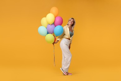 Photo of Happy woman with bunch of colorful balloons on yellow background