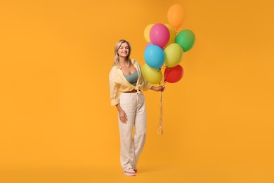 Photo of Happy woman with bunch of colorful balloons on yellow background