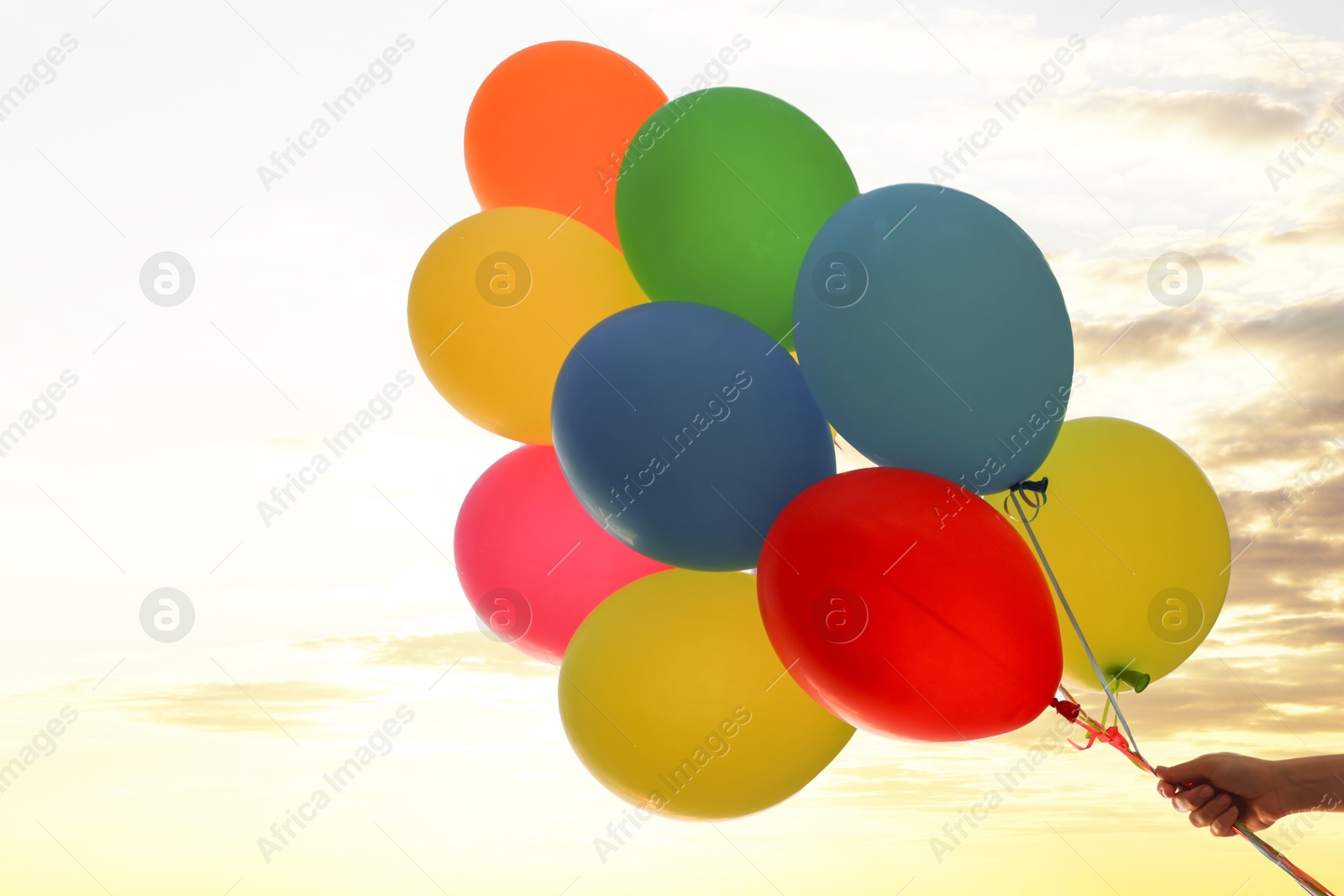 Photo of Woman with bunch of colorful balloons under beautiful sky at sunset, low angle view