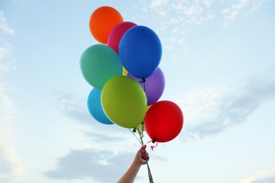 Photo of Woman with bunch of colorful balloons under beautiful sky, low angle view