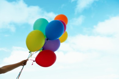 Photo of Woman with bunch of colorful balloons under beautiful sky, closeup. Space for text