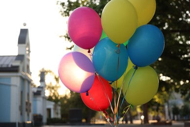 Photo of Bunch of colorful balloons on city street at sunset, closeup