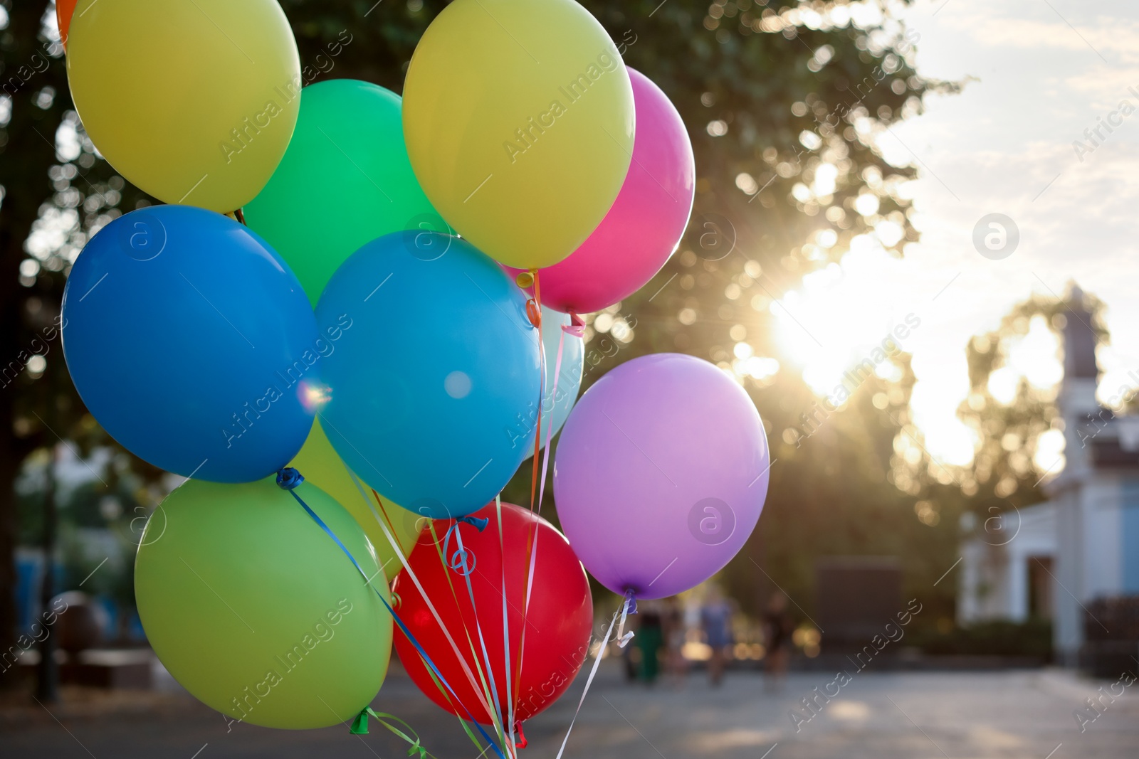 Photo of Bunch of colorful balloons on city street at sunset, closeup