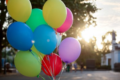 Photo of Bunch of colorful balloons on city street at sunset, closeup