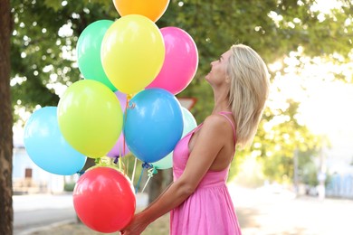 Photo of Woman with bunch of colorful balloons outdoors