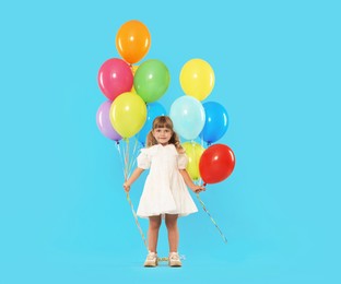 Photo of Cute little girl in dress with many colorful balloons on light blue background