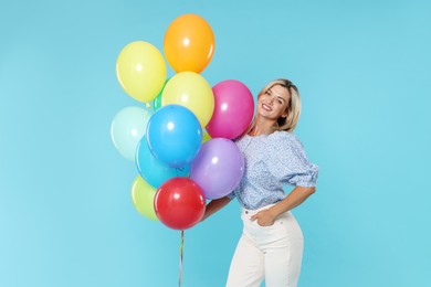 Photo of Smiling woman with bunch of colorful balloons on light blue background