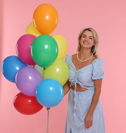 Photo of Smiling woman with bunch of colorful balloons on pink background
