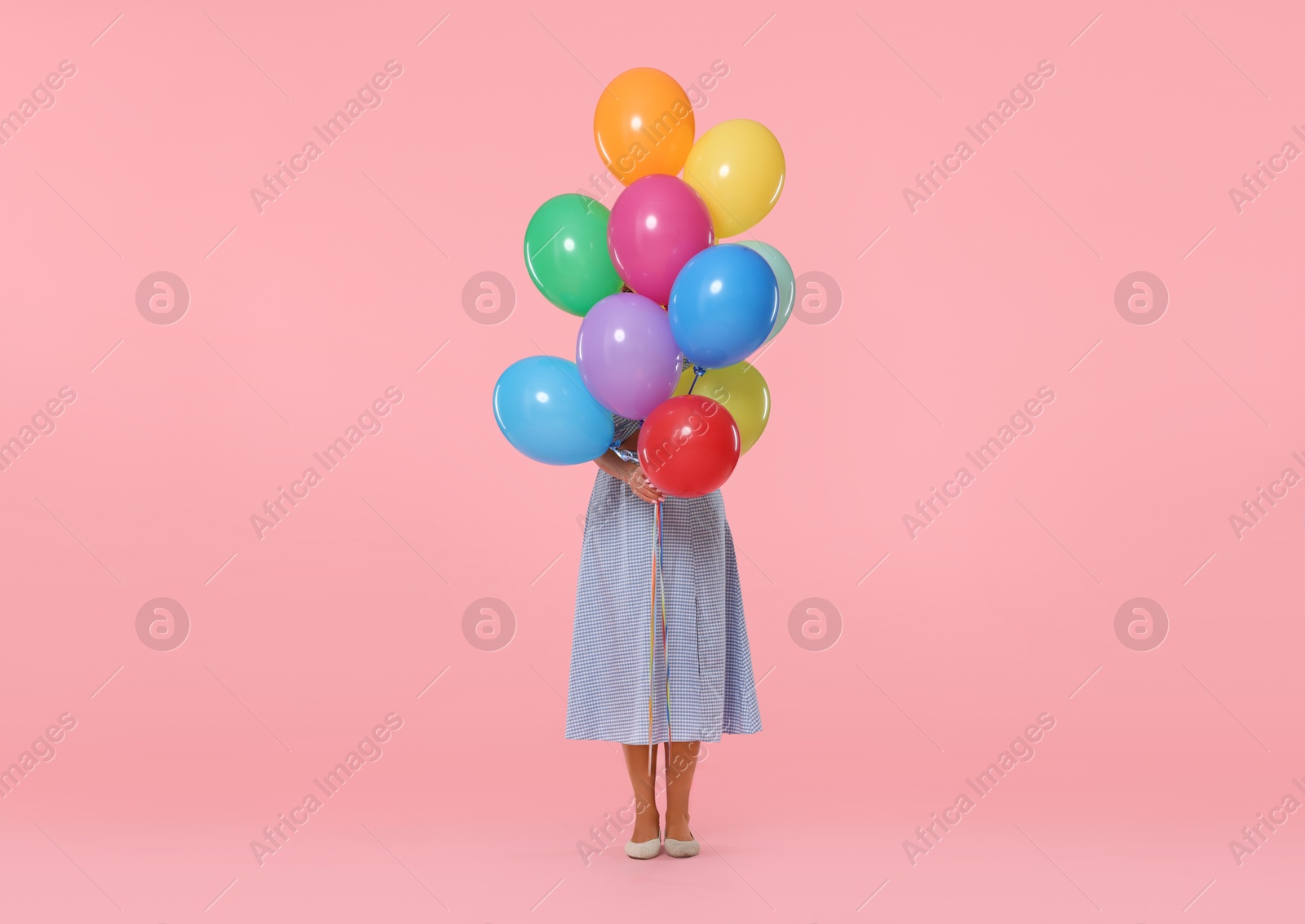 Woman hiding behind bunch of colorful balloons on pink background Photo of Woman hiding behind bunch of colorful balloons on pink background