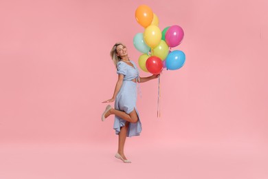 Photo of Smiling woman with bunch of colorful balloons on pink background