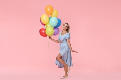 Photo of Smiling woman with bunch of colorful balloons on pink background