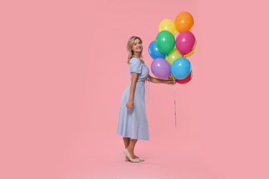 Photo of Smiling woman with bunch of colorful balloons on pink background