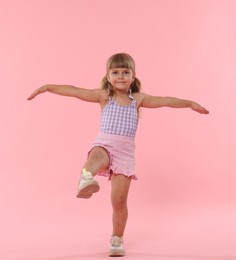 Photo of Cute little girl with wide open arms on pink background