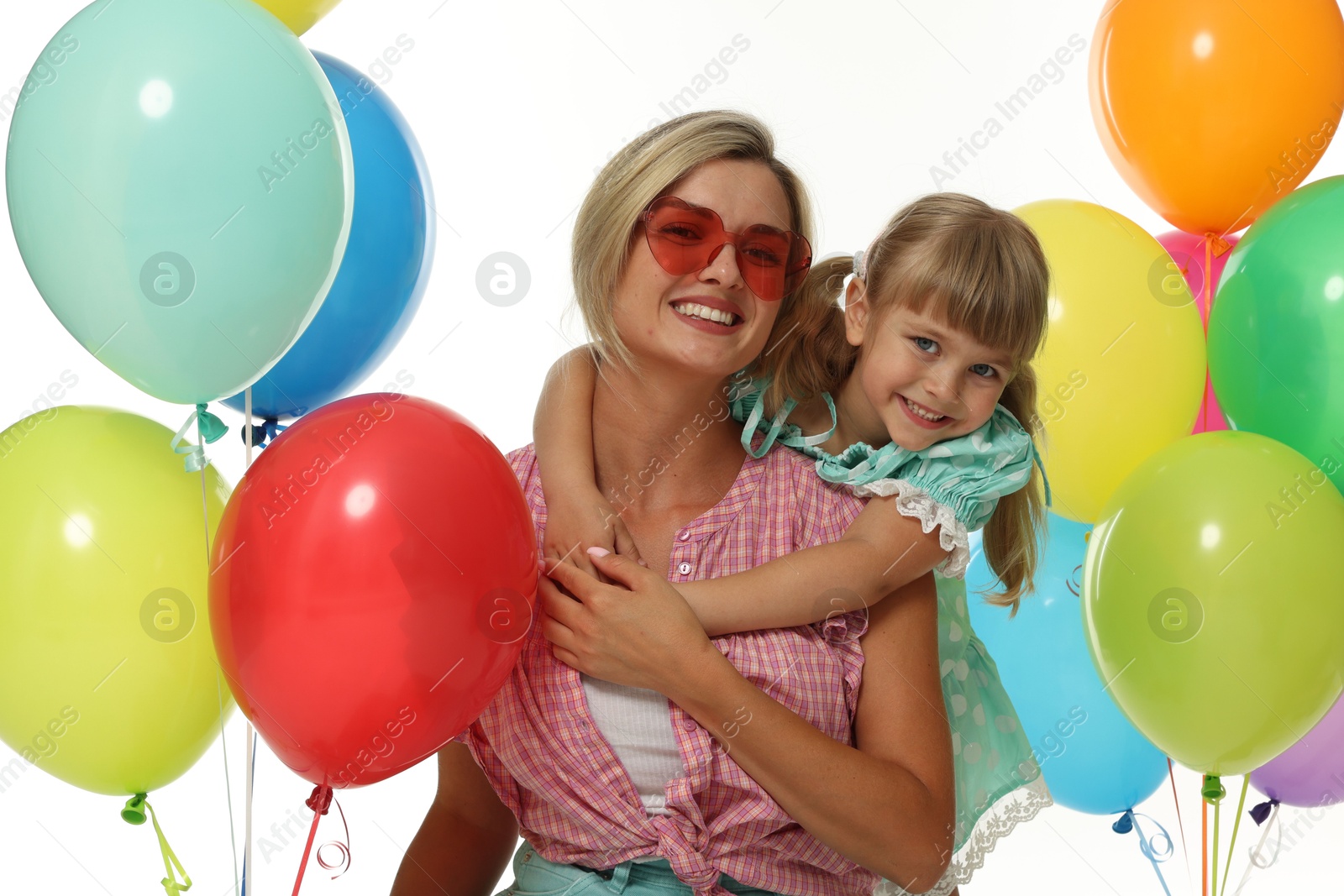 Photo of Happy mother in sunglasses and her little daughter with bunches of colorful balloons on white background