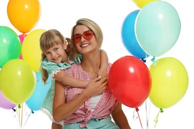 Photo of Happy mother in sunglasses and her little daughter with bunches of colorful balloons on white background