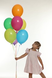 Photo of Cute little girl in dress with bunch of colorful balloons on white background