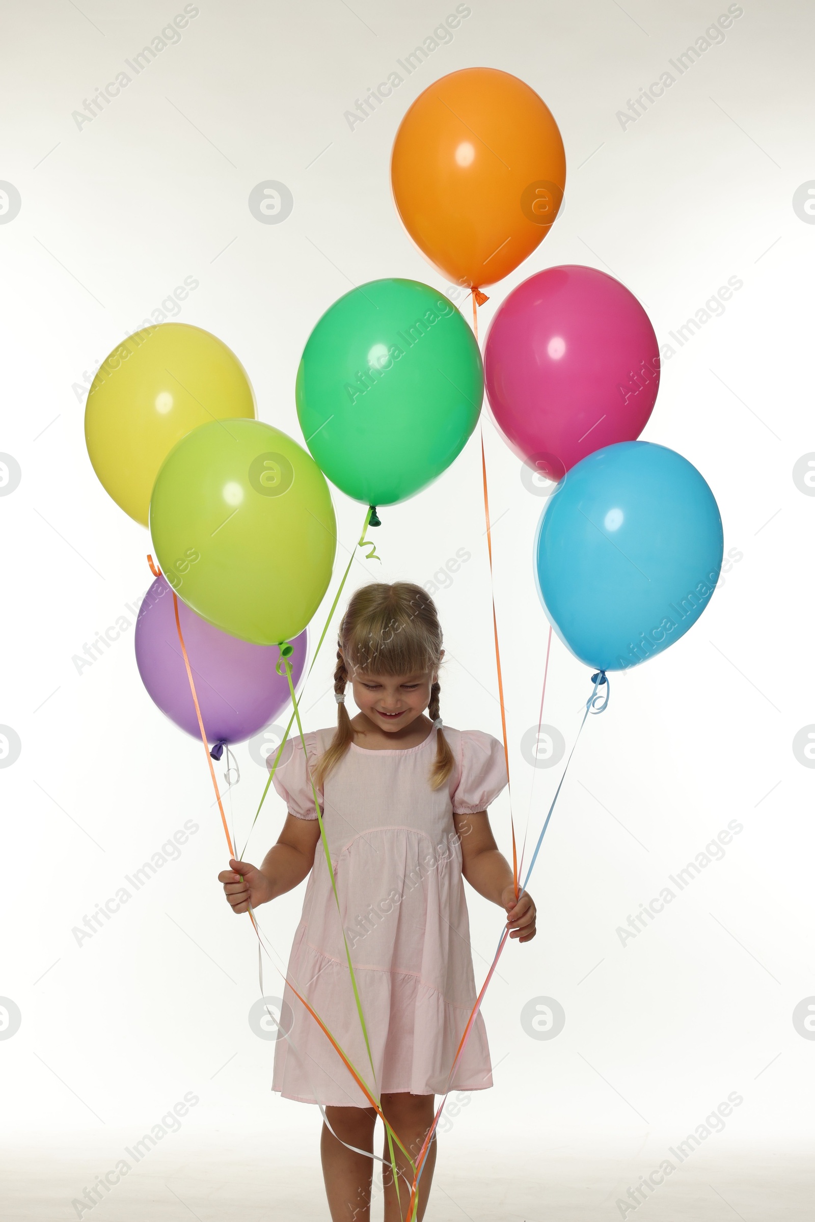 Photo of Happy little girl in dress with many colorful balloons on white background