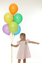 Photo of Cute little girl in dress with bunch of colorful balloons on white background
