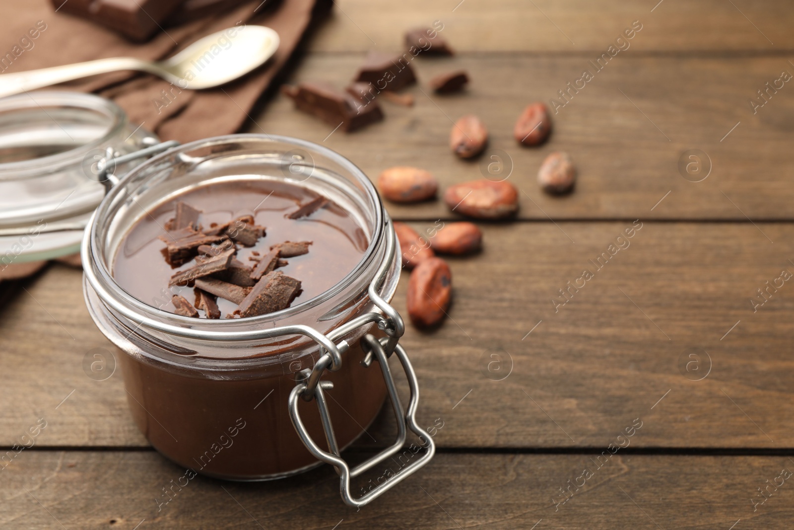 Delicious chocolate panna cotta in glass jar, nuts and spoon on wooden table, closeup. Space for text Photo of Delicious chocolate panna cotta in glass jar, nuts and spoon on wooden table, closeup. Space for text