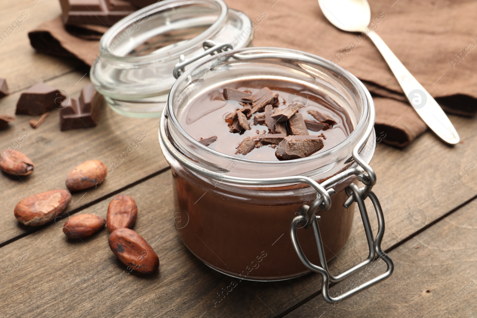 Delicious chocolate panna cotta in glass jar, nuts and spoon on wooden table, closeup Photo of Delicious chocolate panna cotta in glass jar, nuts and spoon on wooden table, closeup