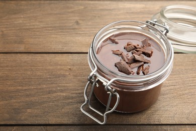 Photo of Delicious chocolate panna cotta in glass jar on wooden table, closeup. Space for text