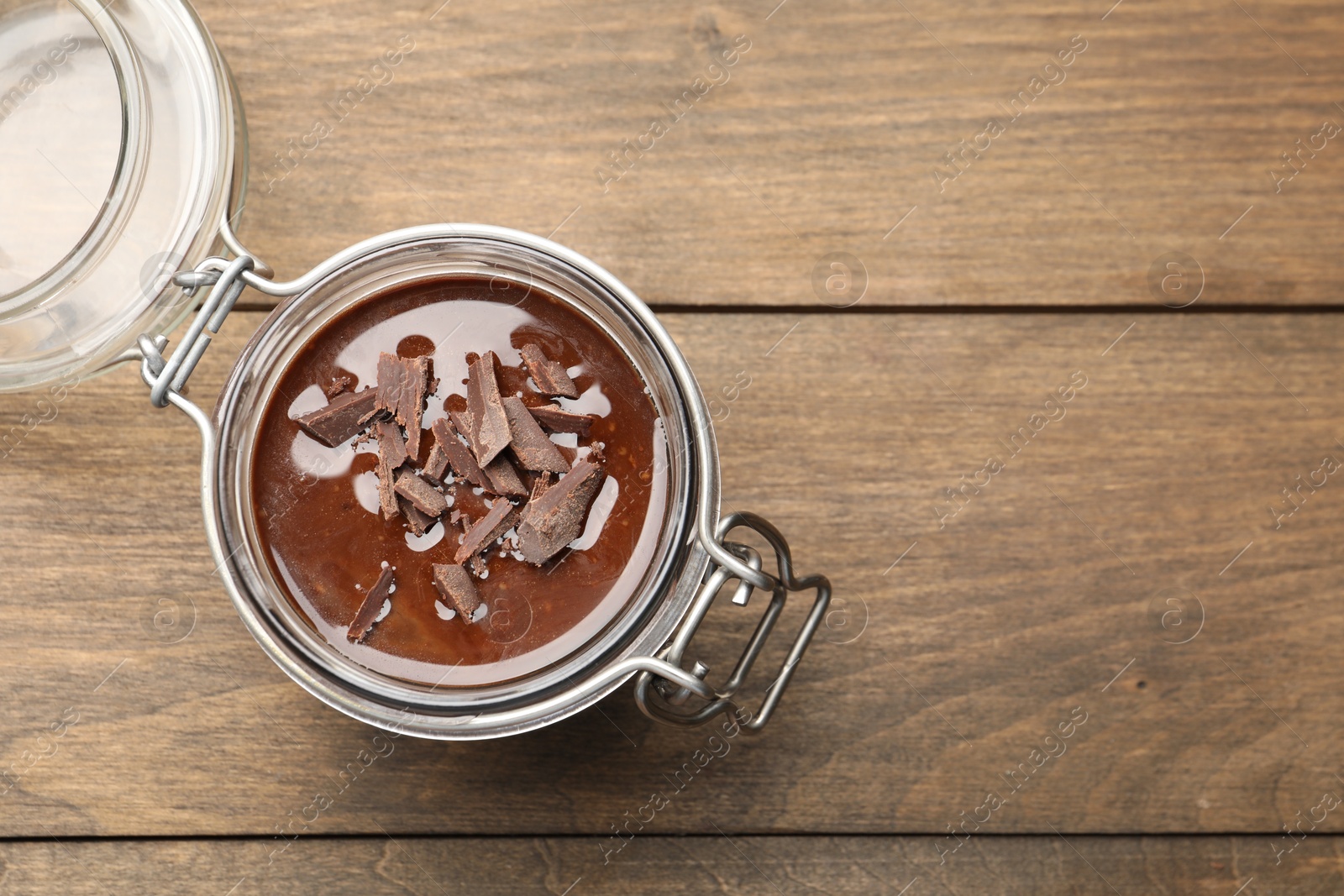 Photo of Delicious chocolate panna cotta in glass jar on wooden table, top view. Space for text