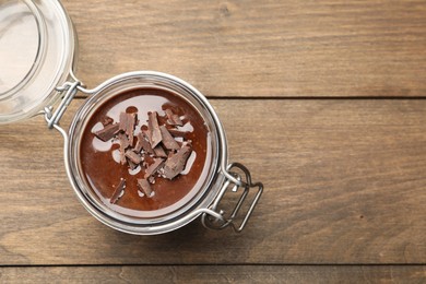 Photo of Delicious chocolate panna cotta in glass jar on wooden table, top view. Space for text
