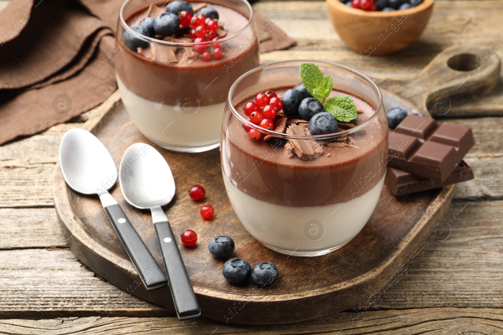 Delicious panna cotta with chocolate, berries and mint on wooden table, closeup Photo of Delicious panna cotta with chocolate, berries and mint on wooden table, closeup