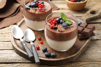 Photo of Delicious panna cotta with chocolate, berries and mint on wooden table, closeup