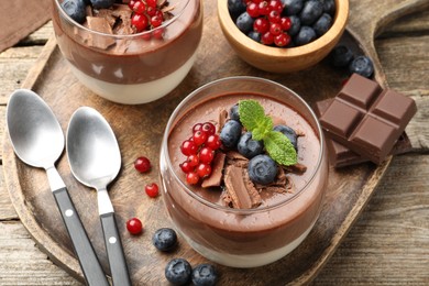 Photo of Delicious panna cotta with chocolate, berries and mint on wooden table, above view