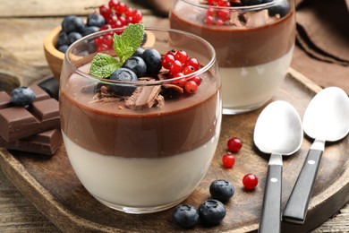 Photo of Delicious panna cotta with chocolate, berries and mint on wooden table, closeup