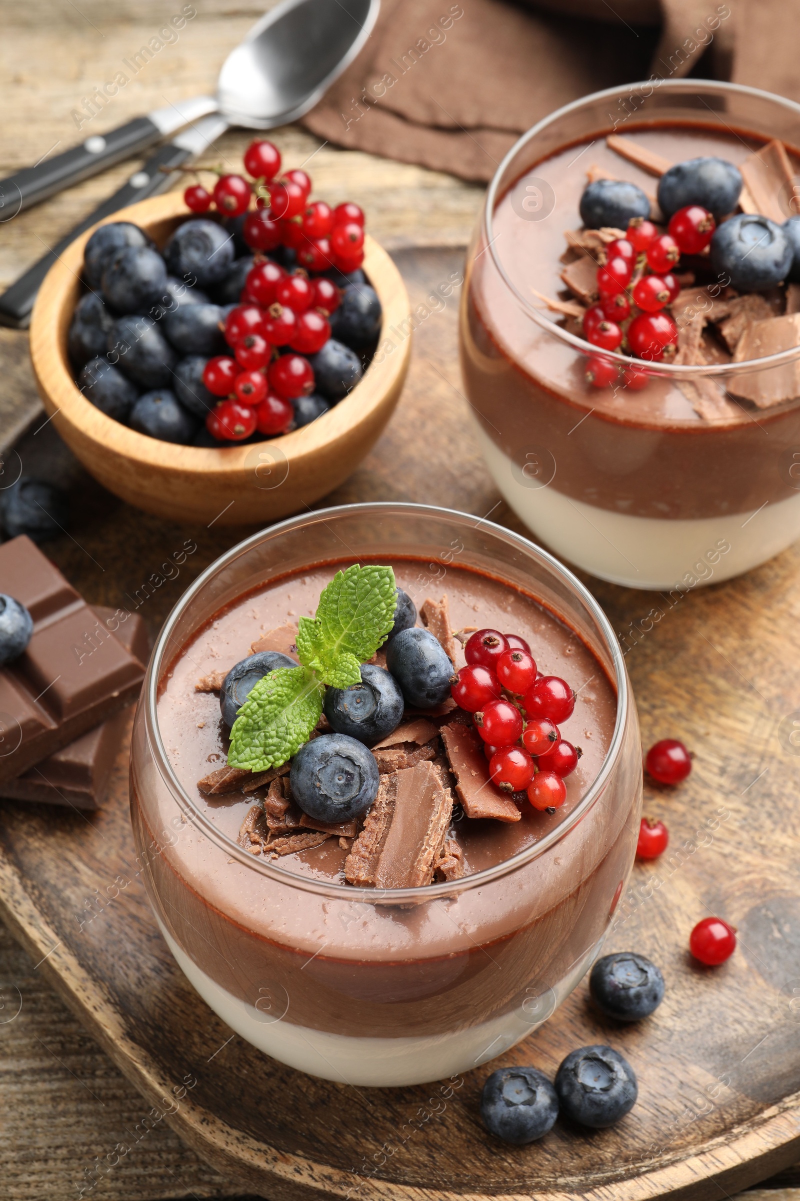 Photo of Delicious panna cotta with chocolate, berries and mint on table, closeup