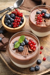Photo of Delicious panna cotta with chocolate, berries and mint on table, closeup